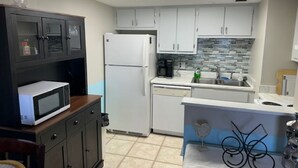 A compact kitchen with white cabinets, a microwave, a refrigerator, and a tiled backsplash. - 2-Bedroom 2-Bathroom 5th "TOP" Floor Condo in Stunning Ormond Beach with AC (Ormond Beach)