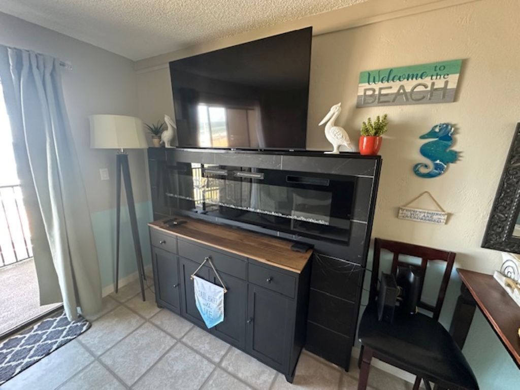 Una cocina con televisor integrado, un comedor con una silla y una pared con un cartel de bienvenida.