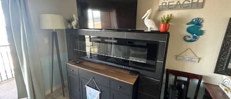 Una cocina con televisor integrado, un comedor con una silla y una pared con un cartel de bienvenida.