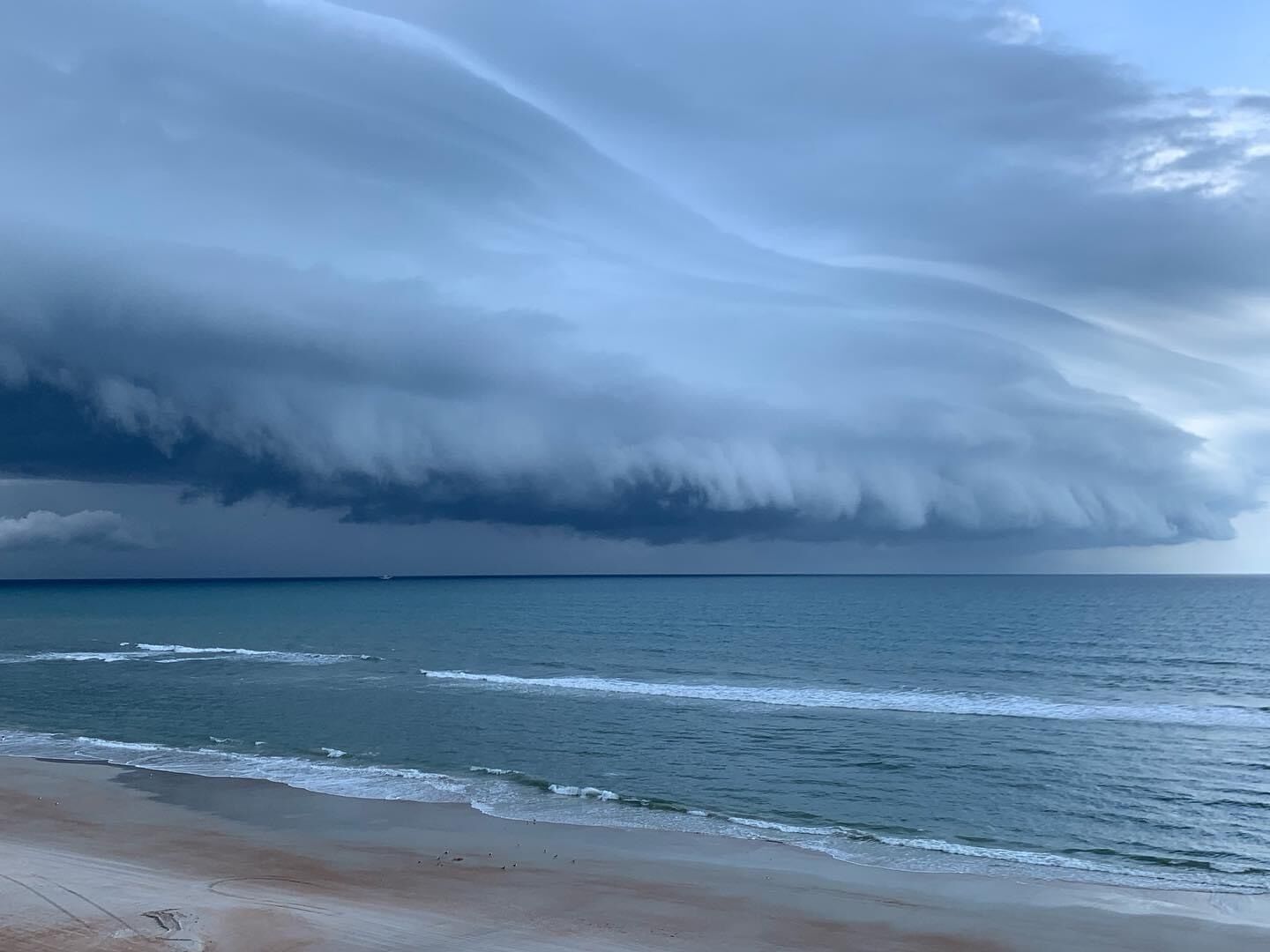 En strand med bølger og en overskyet himmel.