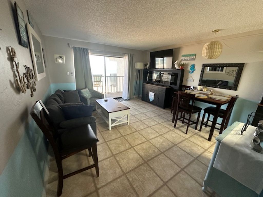 A living room with a sofa, a coffee table, and a dining area with chairs and a table.
