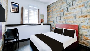 A bedroom with a bed, a chair, a window with blinds, a picture on the wall, and a brick wall. - Super Collection O Rajkumar Road (Mysore)