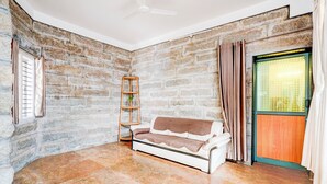 A room with a stone wall, a white sofa, a wooden ladder, and a window with curtains. - Super Collection O Rajkumar Road (Mysore)