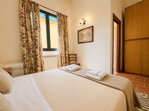 A bedroom with a bed, a chair, a wooden wardrobe, a radiator, and a window with curtains. - Tenuta Gaetano Spadaro, Maurino Apartment (Capannori)
