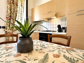 A kitchen with wooden cabinets, a gas stove, and a coffee maker. - Tenuta Gaetano Spadaro, Maurino Apartment (Capannori)