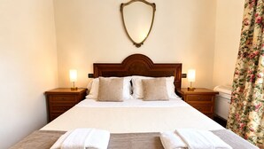 A hotel room with a large bed, two bedside tables, a mirror, and a floral curtain. - Tenuta Gaetano Spadaro, Maurino Apartment (Capannori)