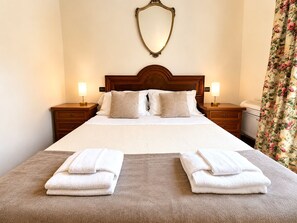 A hotel room with a large bed, two bedside tables, a mirror, and a floral curtain. - Tenuta Gaetano Spadaro, Maurino Apartment (Capannori)