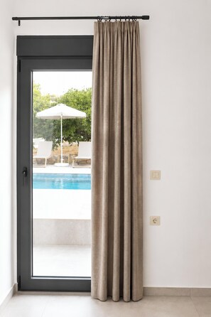 A room with a sliding glass door leading to an outdoor area with a pool and lounge chairs. - Villa Mark (Glossa)