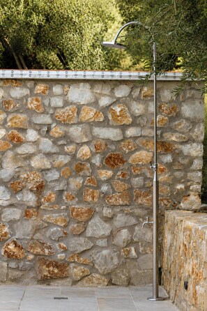 A stone wall with a metal structure, possibly a light fixture, and a tiled floor. - Villa Mark (Glossa)