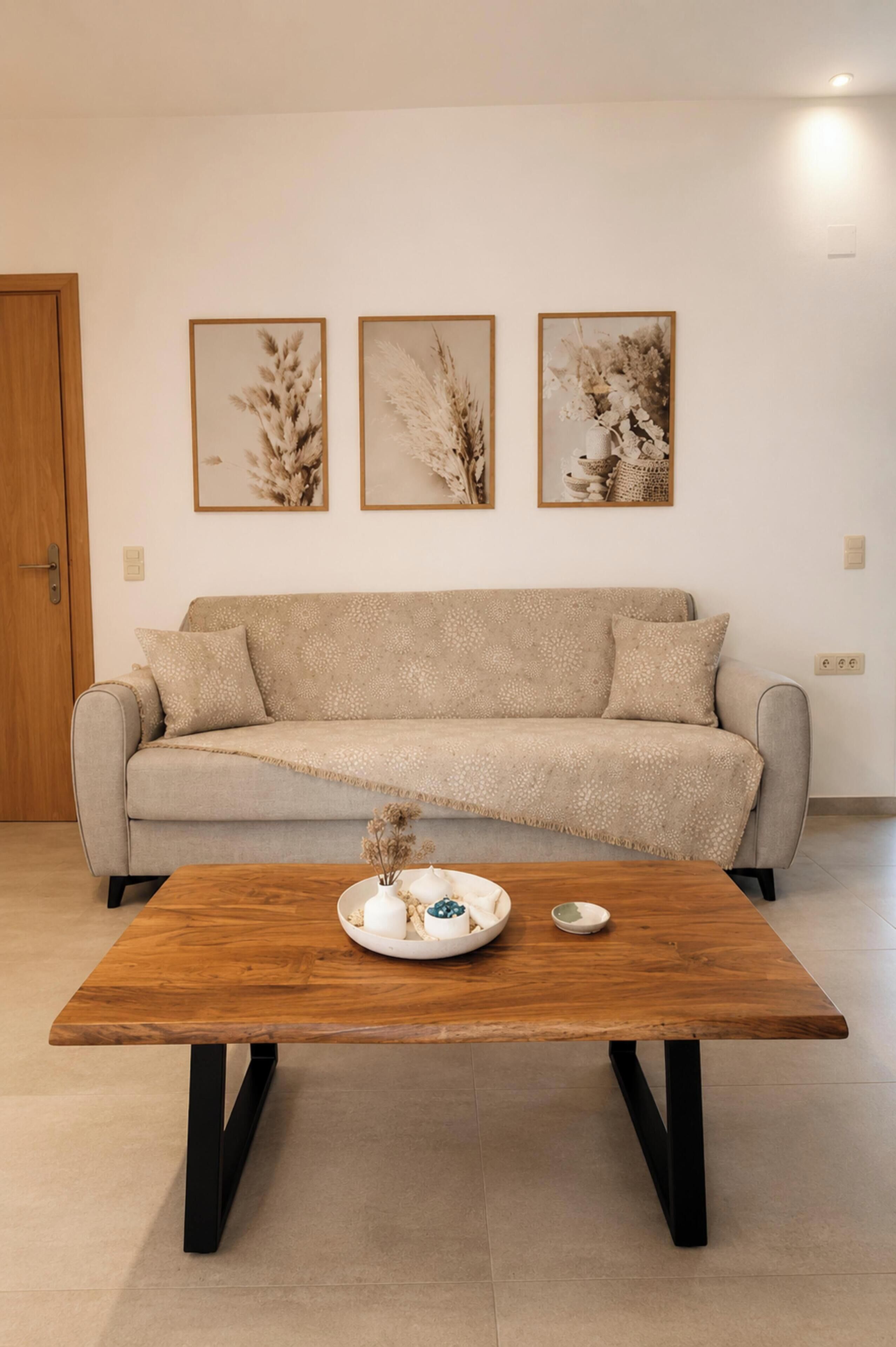 A living room with a sofa, a coffee table, and three framed pictures on the wall.