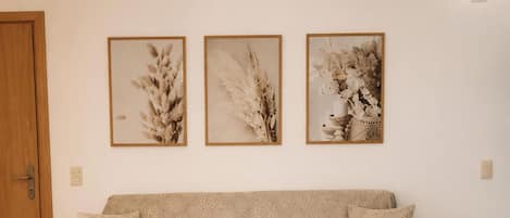 Un salón con un sofá, una mesa de centro y tres cuadros en la pared.