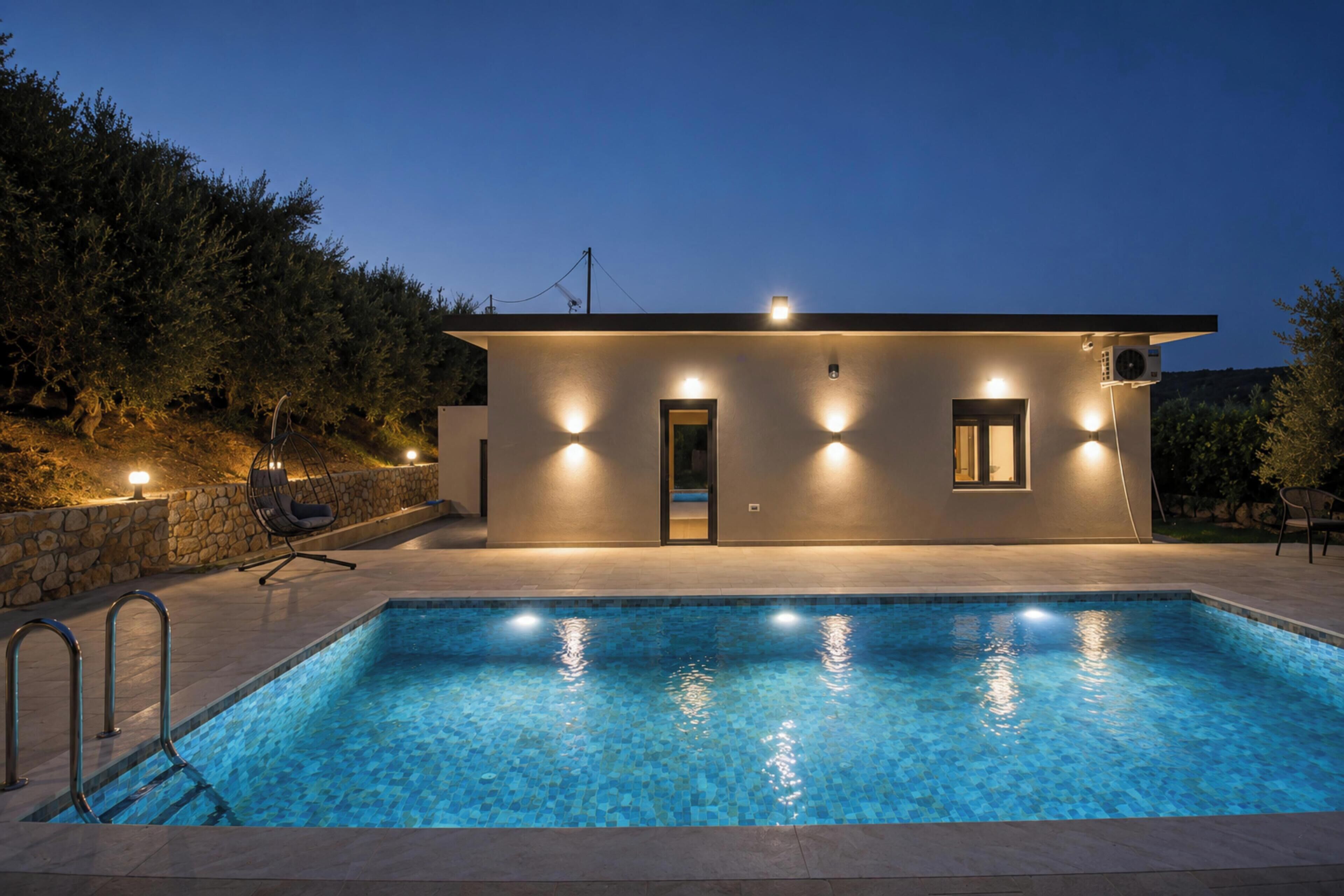 A modern house with a swimming pool, stone walls, and outdoor seating.
