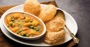 A plate with a curry dish, bread, and a spoon. - Hotel The Banaras inn Varanasi (Varanasi)