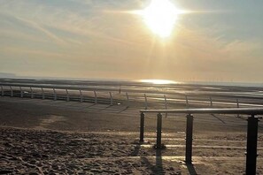 Ein Strand mit einer Metallreling und blauem Himmel.