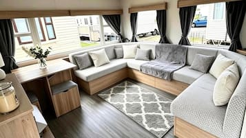 A cozy RV interior with a sectional sofa, a small table, and a rug.