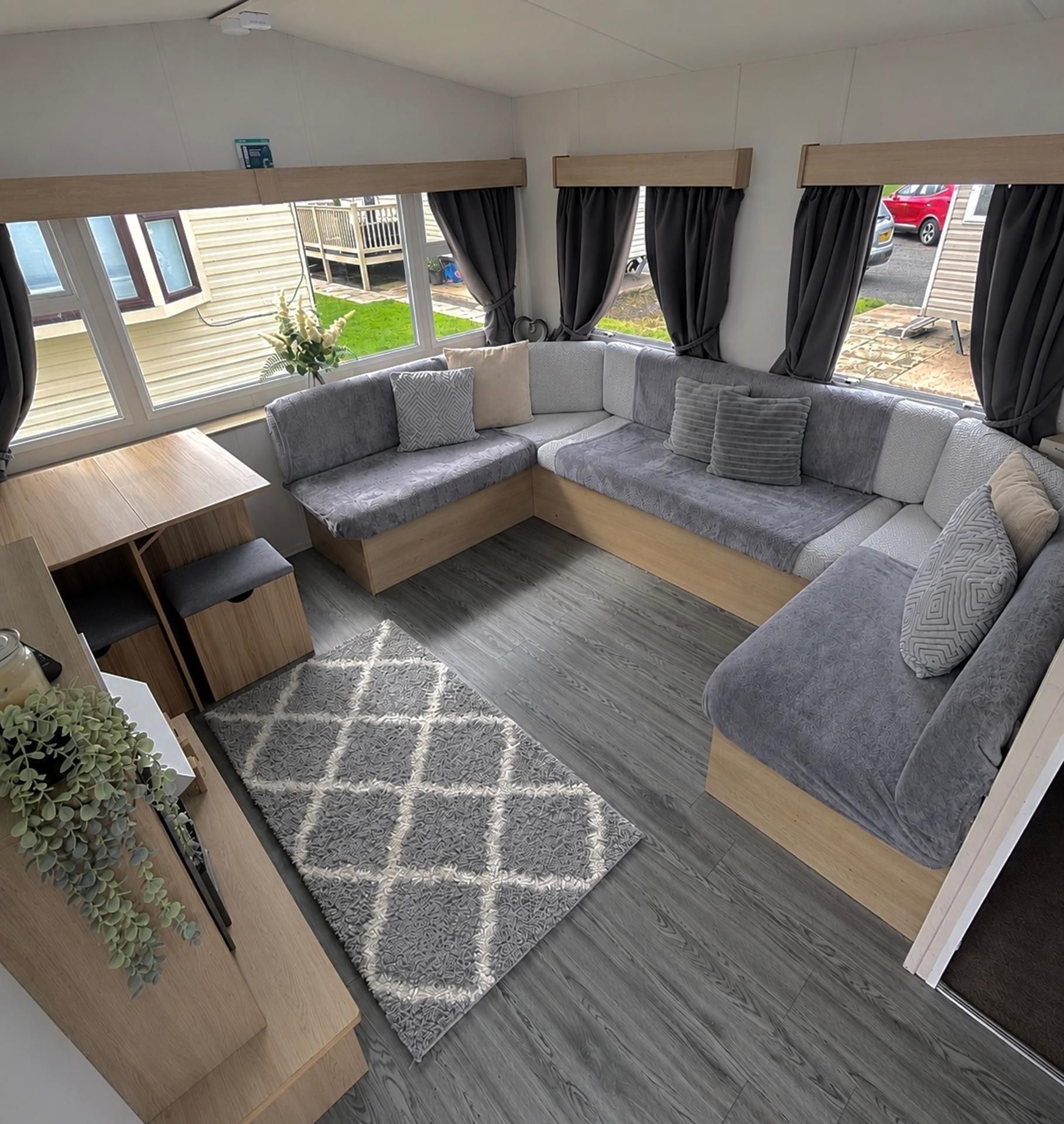 A modern RV interior with a sectional sofa, a small table, and a rug.