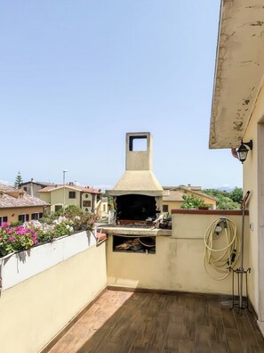 A rooftop with a stone barbecue grill, a hose, and a potted plant. - Casa Paola - Iglesias (Iglesias)