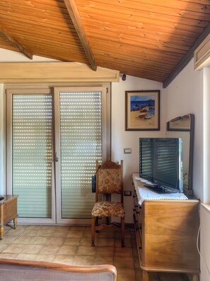 A room with a wooden ceiling, a television, a chair, and a bed. - Casa Paola - Iglesias (Iglesias)