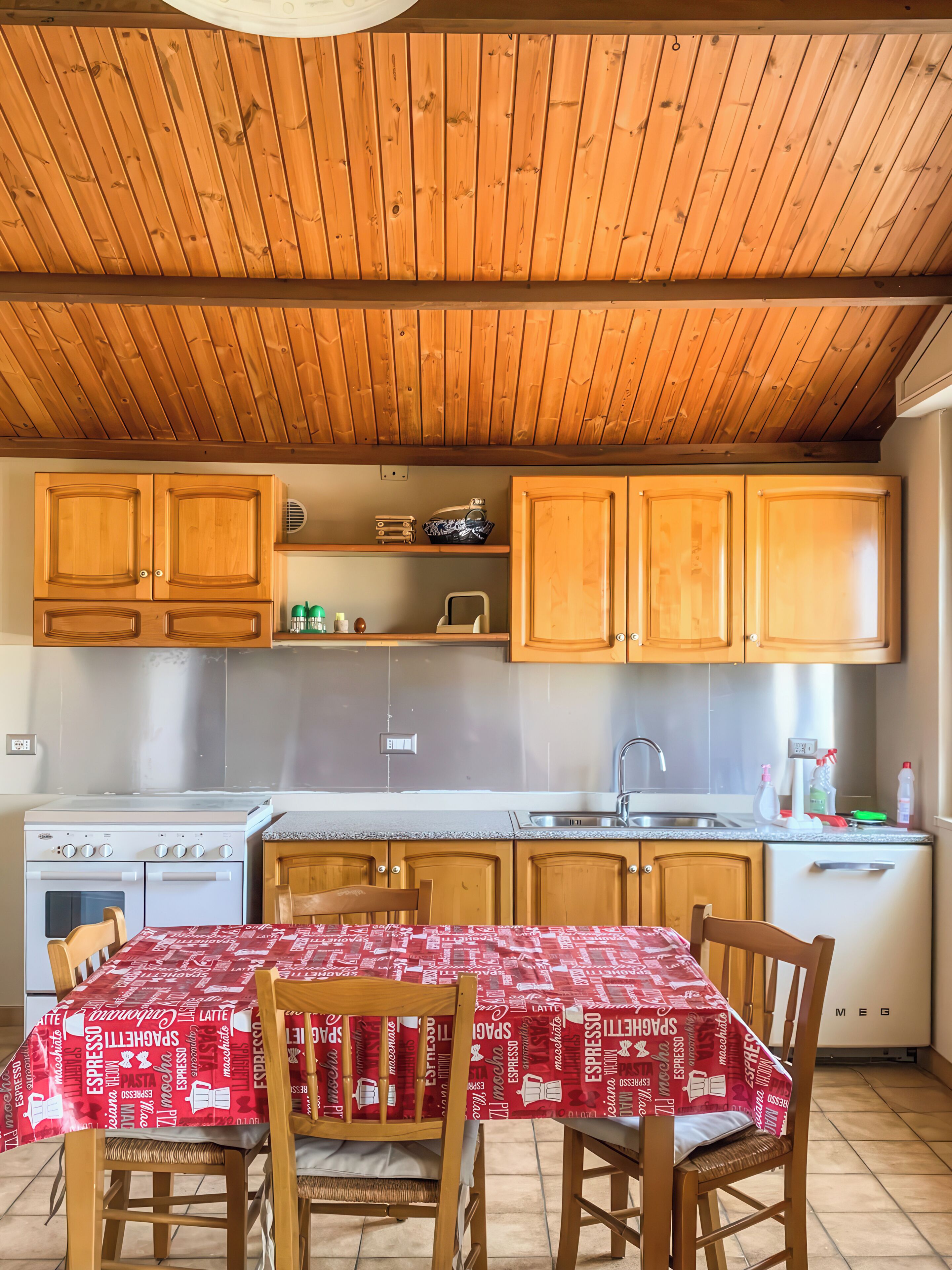 Uma cozinha com armários de madeira, fogão e mesa com cadeiras.