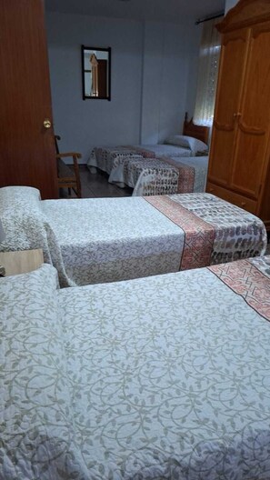 A room with three beds, a wooden wardrobe, and a mirror on the wall. - Bedmar Farmhouse (Bedmar)