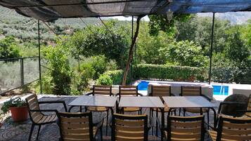 Une terrasse extérieure avec des tables et des chaises, une piscine et une vue sur le paysage environnant.