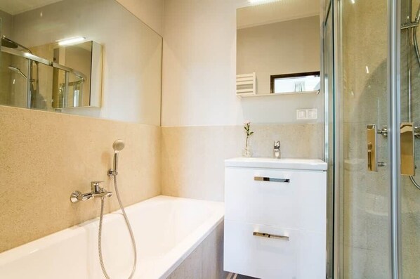 A modern bathroom with a bathtub, a glass shower enclosure, and a vanity with a mirror.