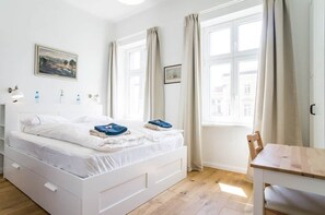 Un dormitorio con una cama, una mesa y una ventana.
