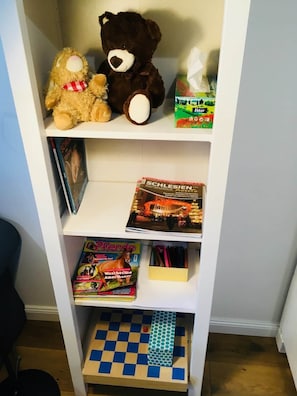 A bookshelf with a teddy bear, a book, and a box of tissues.