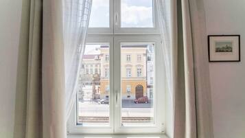 A room with a large window, curtains, and a framed picture on the wall.