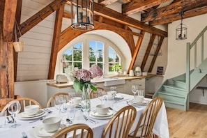 A dining area with a table set for four, wooden chairs, and a large window with a view of greenery. - Villa Meinecke - Apartment 1 'Park Szczytnicki' (Wrocław)