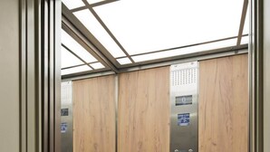 An elevator with wooden paneling and a digital display.