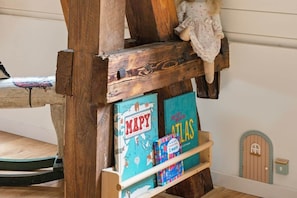A wooden shelf with books and a doll.