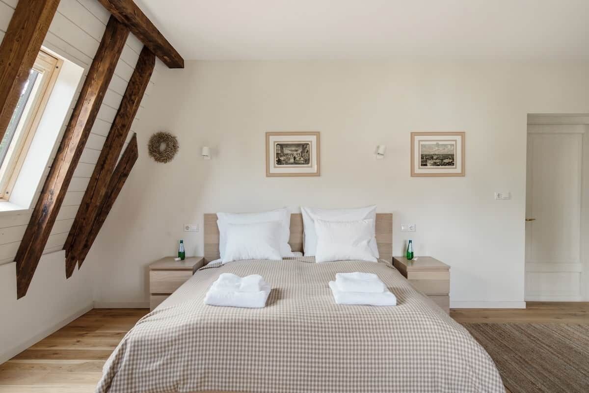 A bedroom with a checkered bedspread, two bedside tables with lamps, and framed pictures on the wall.
