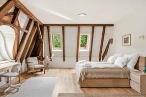 A bedroom with a sloped ceiling, wooden beams, a bed, a desk, and a chair. - Villa Meinecke - Apartment 4 'Zoo' (Wrocław)