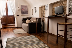 A cozy living room with a sofa, a television, and a wooden table. - Charming Apartment Near Bari & Alberobello (Bitritto)