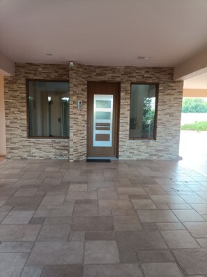 A modern building entrance with a stone facade, a large door with a glass panel, and a tiled floor. - Perfect 1-bedroom apartment with AC in charming Kiato (Kiato)