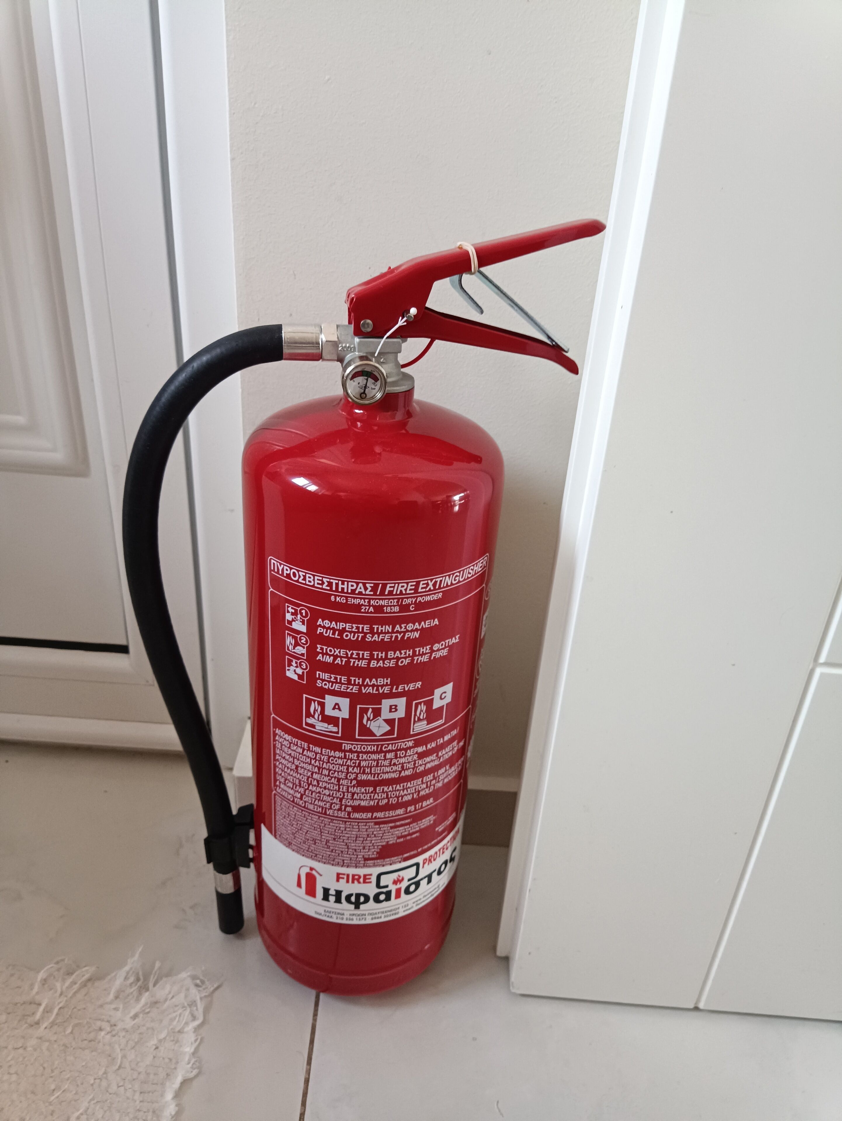 A red fire extinguisher mounted on a wall near a door.