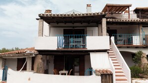Un edifici de dues plantes amb un balcó, una escala i una petita zona d'estar a l'exterior.
