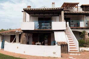 A two-story building with a balcony, a staircase, and a small outdoor seating area. - Vera Holiday Home by Wonderful Italy (Olbia)