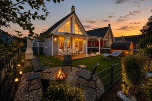 Ein Haus mit einer Terrasse, Sitzgelegenheiten im Freien und einer Feuerstelle.