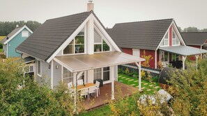 Una propiedad residencial con un patio cubierto, un jardín cercado y una casa vecina.