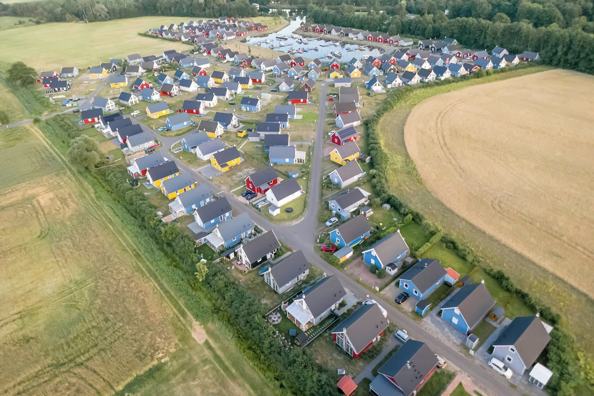 An aerial view of a residential area with houses, roads, and a body of water.