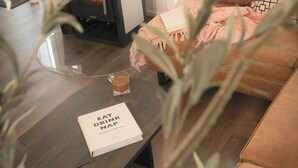 A cozy living room with a modern fireplace, a comfortable sofa, a glass coffee table, and a book titled 'EAT DRINK NAP'. - Design retreat with sauna near Berlin (Wandlitz)