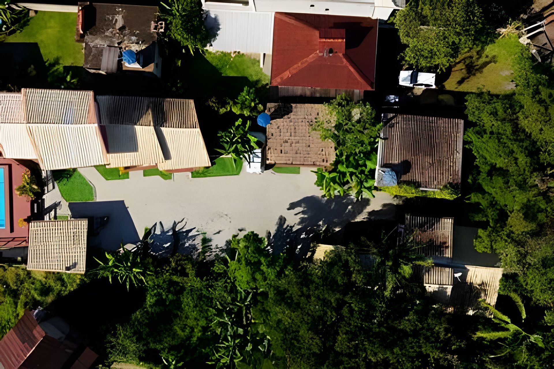 An aerial view of a residential area with multiple houses, a central open space, and surrounding greenery.