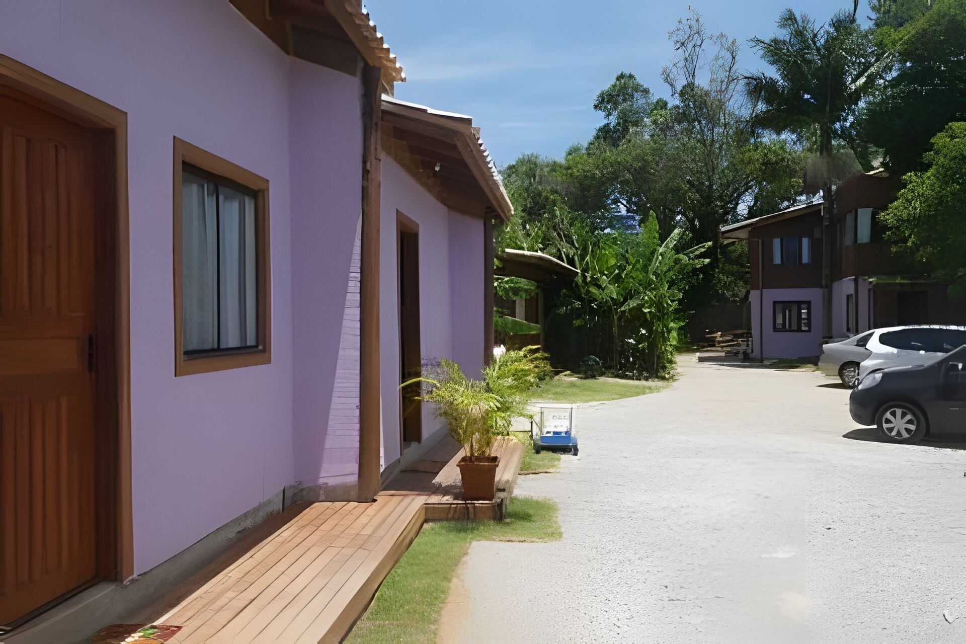 A residential street with houses, a driveway, and parked cars.