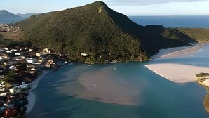 Un paisaje costero con una colina destacada, una playa y un pequeño poblado.