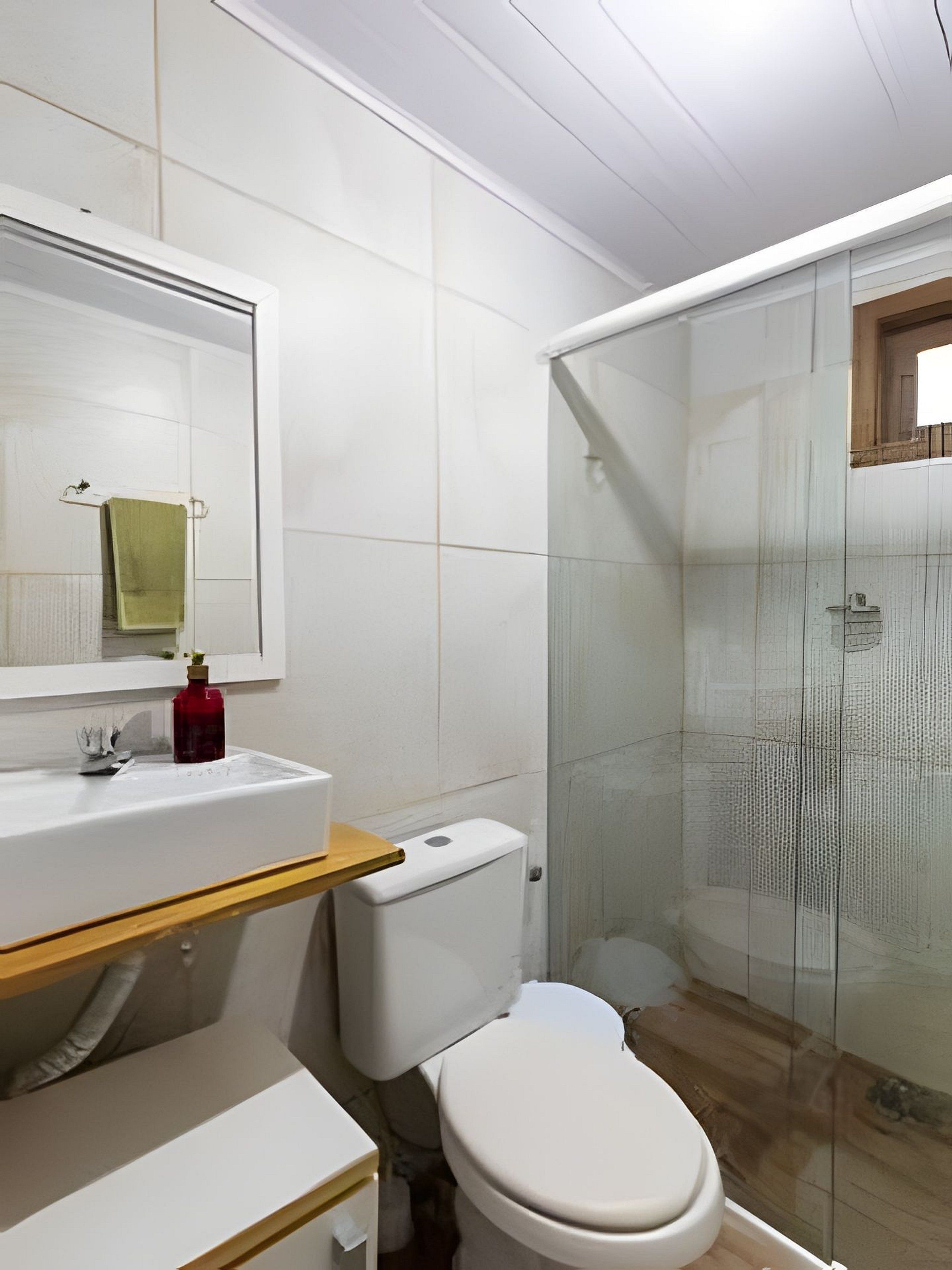 Ein Badezimmer mit Toilette, Waschbecken und einer gläsernen Duschkabine.