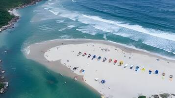 An aerial view of a beach with a sandy area and a row of beach chairs.