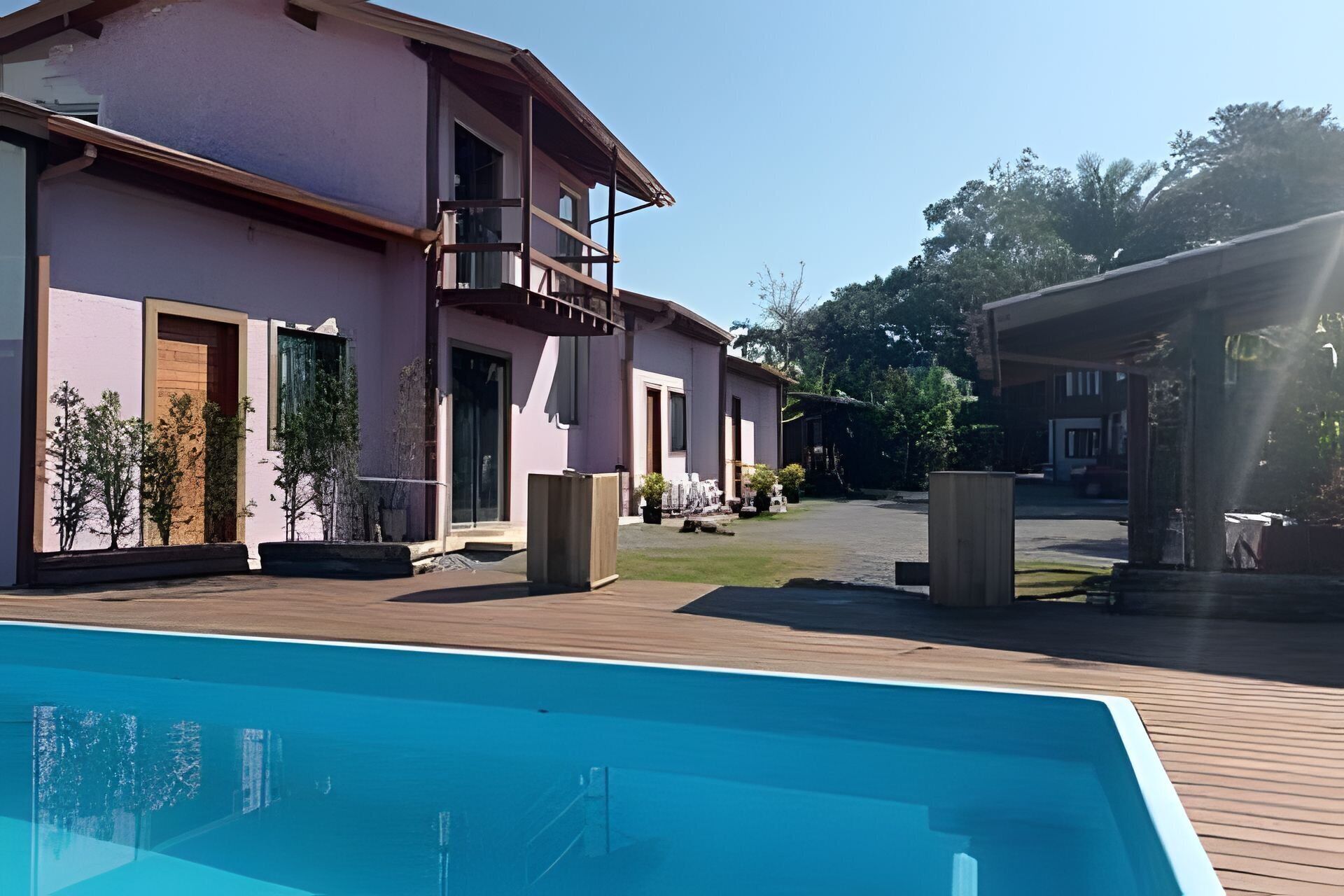A modern building with a pool, outdoor seating, and a covered area.