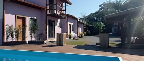A modern building with a pool, outdoor seating, and a covered area.